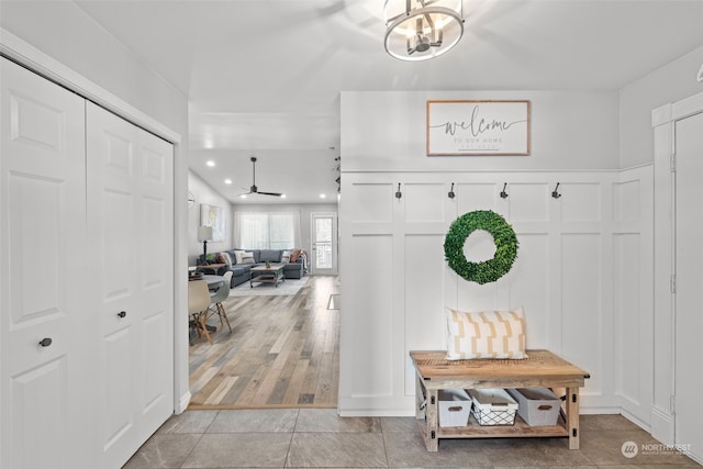 mudroom featuring ceiling fan with notable chandelier