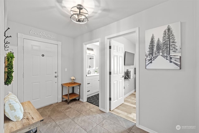 tiled entrance foyer with sink and an inviting chandelier