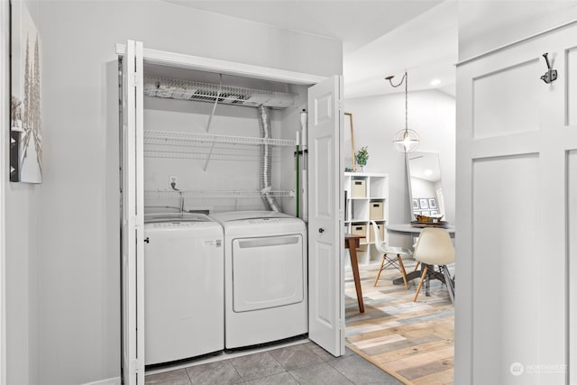 laundry area featuring washing machine and clothes dryer and light hardwood / wood-style floors