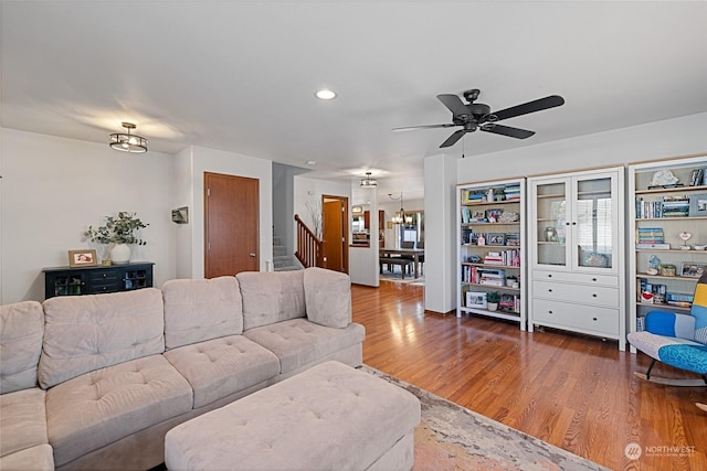 living room with ceiling fan with notable chandelier and hardwood / wood-style floors