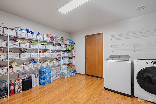 laundry room with washing machine and clothes dryer and light wood-type flooring