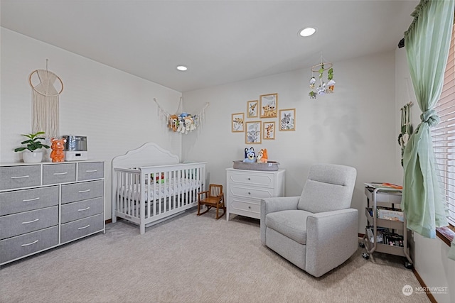 carpeted bedroom featuring a nursery area