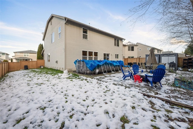 snow covered rear of property with a covered pool