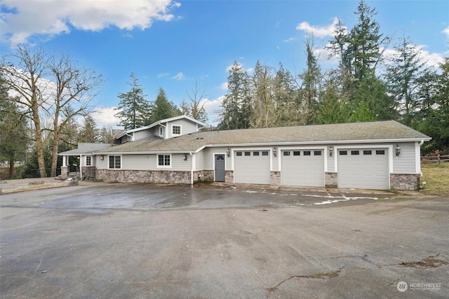 exterior space featuring a garage, stone siding, and driveway