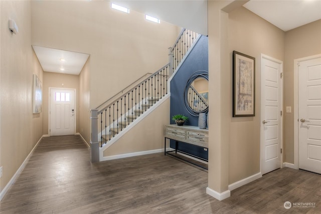 entryway featuring a towering ceiling and dark wood-type flooring