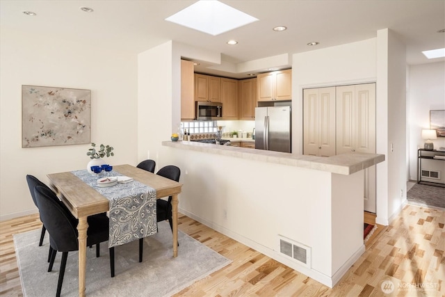 dining room featuring visible vents, recessed lighting, a skylight, and light wood-style floors