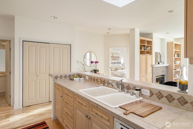 kitchen with light countertops, recessed lighting, a fireplace, light wood-style floors, and a sink