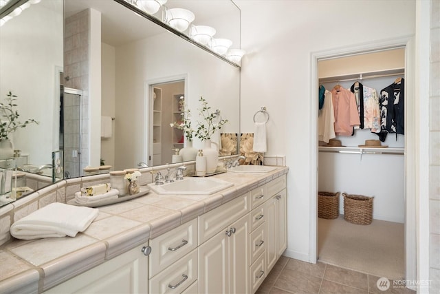 full bathroom with tile patterned floors, double vanity, a shower stall, and a sink