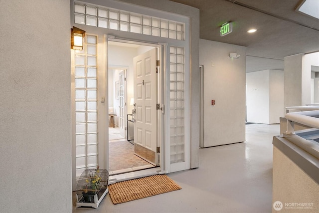 hall featuring recessed lighting, a textured wall, and concrete floors