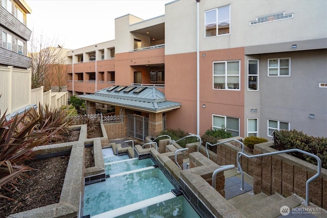 view of pool with fence and a hot tub