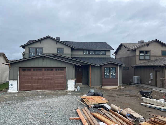 view of front of property with gravel driveway, central AC unit, board and batten siding, and an attached garage