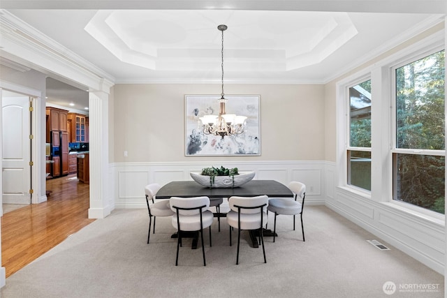 carpeted dining room with a chandelier, crown molding, and a raised ceiling