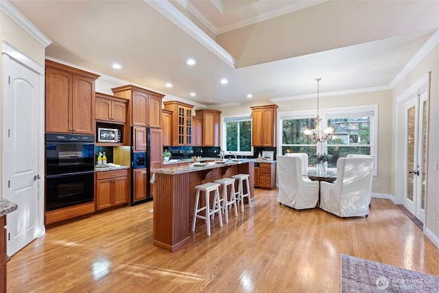 kitchen with tasteful backsplash, black double oven, crown molding, and a center island