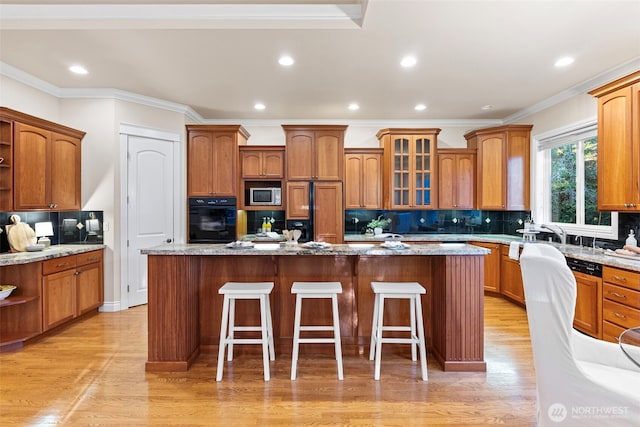 kitchen with light stone countertops, a kitchen island, black oven, and a kitchen breakfast bar