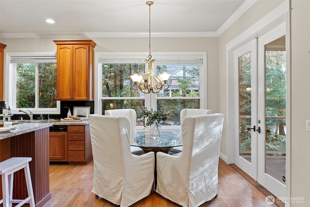 dining space featuring crown molding, a healthy amount of sunlight, light hardwood / wood-style floors, and french doors