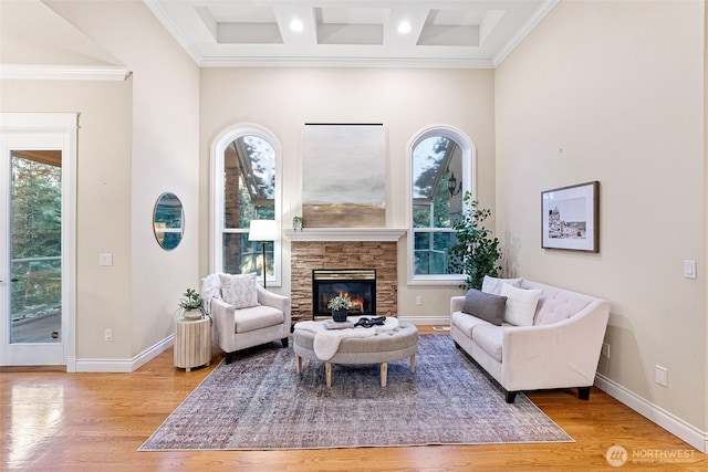 living room with light hardwood / wood-style flooring, coffered ceiling, a fireplace, ornamental molding, and beamed ceiling