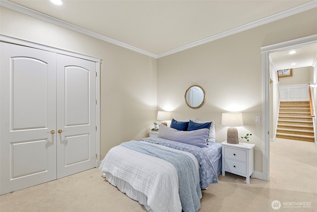 bedroom featuring light colored carpet, ornamental molding, and a closet