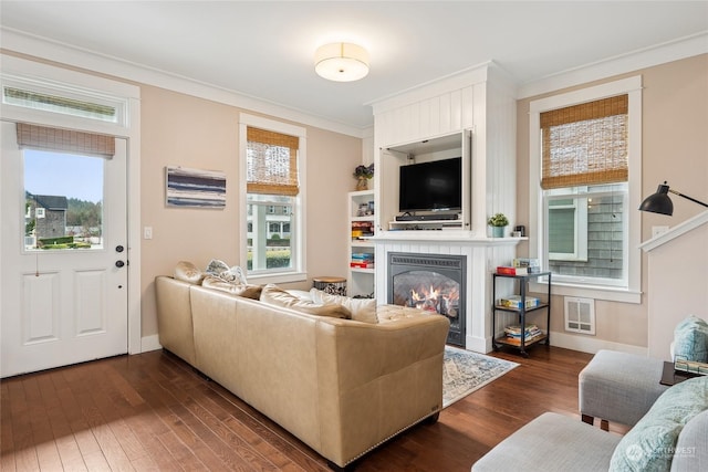 living room featuring dark hardwood / wood-style flooring, crown molding, and a healthy amount of sunlight