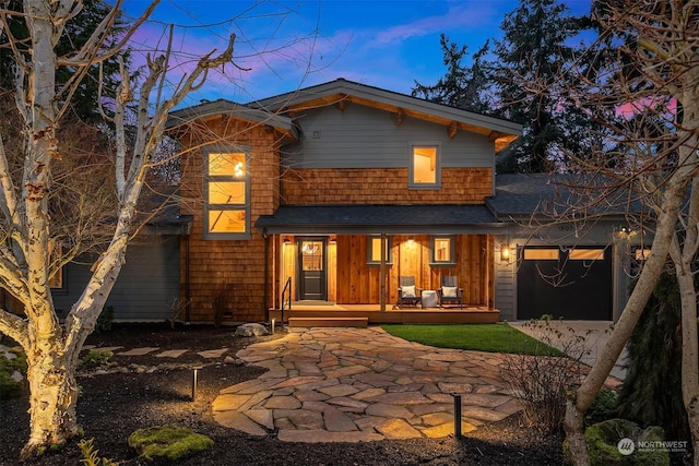 back house at dusk featuring a porch and a garage