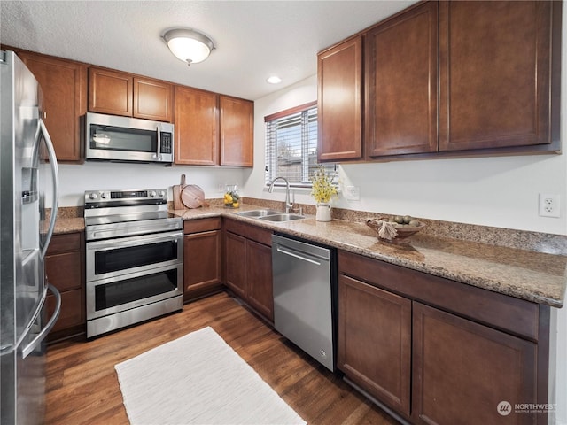 kitchen featuring light stone countertops, appliances with stainless steel finishes, sink, and dark hardwood / wood-style flooring