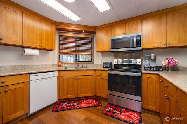 kitchen featuring light stone countertops, appliances with stainless steel finishes, sink, and dark hardwood / wood-style floors