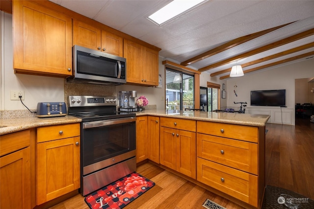 kitchen featuring stainless steel appliances, kitchen peninsula, vaulted ceiling, and light hardwood / wood-style flooring