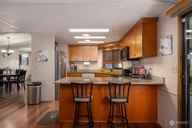 kitchen featuring sink, hardwood / wood-style flooring, a kitchen breakfast bar, white dishwasher, and kitchen peninsula