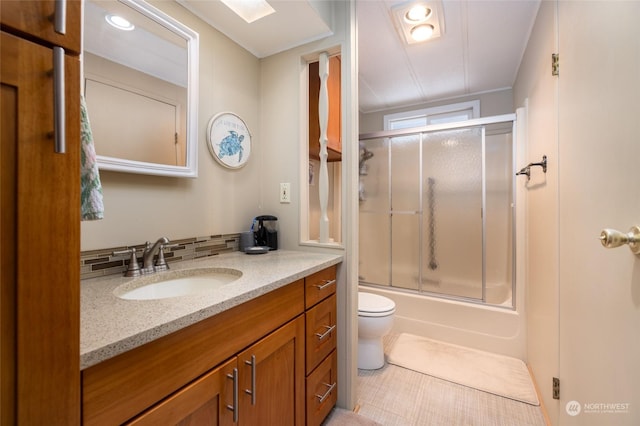 full bathroom featuring backsplash, shower / bath combination with glass door, tile patterned flooring, vanity, and toilet