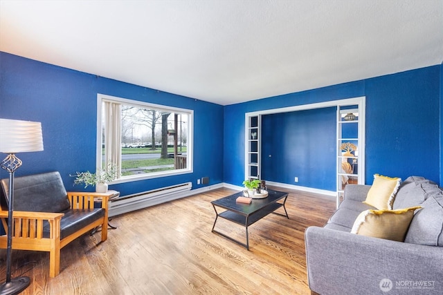 living area featuring a baseboard heating unit, baseboards, and wood finished floors