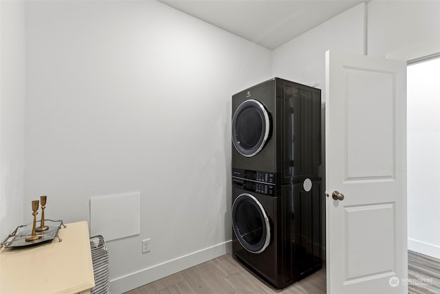 washroom with stacked washing maching and dryer and light hardwood / wood-style flooring