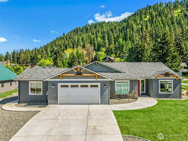 9783 Dye Rd, Leavenworth, WA 98826 - view of front of house with a shingled roof, an attached garage, a front lawn, a view of trees, and concrete driveway
