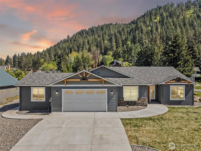 9783 Dye Rd, Leavenworth, WA 98826 - ranch-style house featuring a shingled roof, an attached garage, a front lawn, a view of trees, and concrete driveway