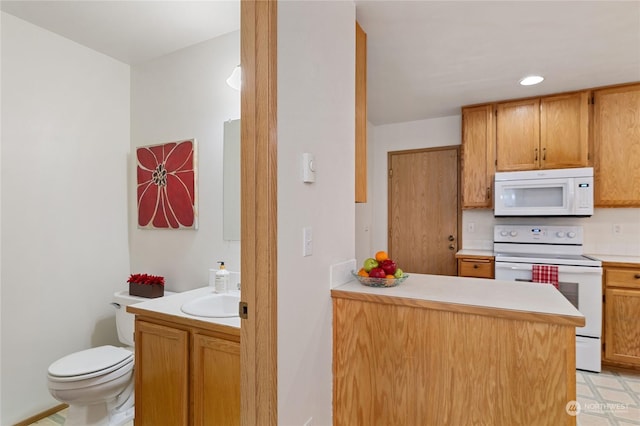 kitchen with white appliances, kitchen peninsula, and sink