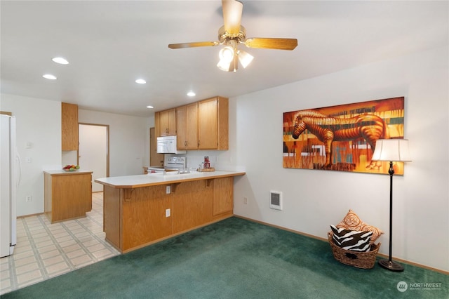 kitchen featuring white appliances, a breakfast bar area, ceiling fan, carpet floors, and kitchen peninsula