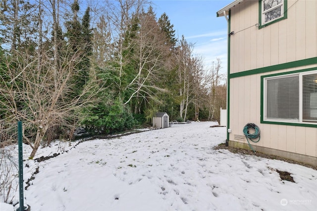 snowy yard with a storage shed