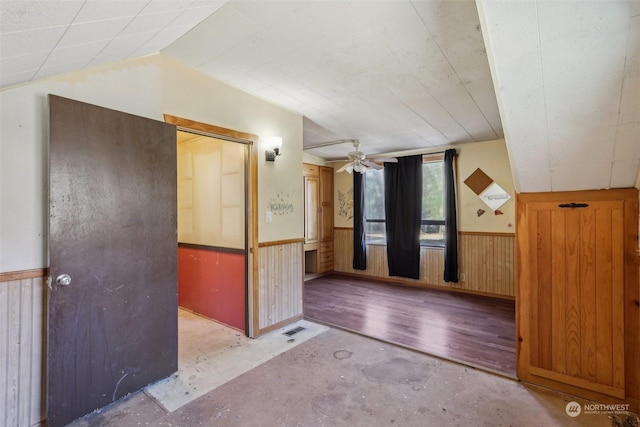 bonus room featuring lofted ceiling, ceiling fan, and wood walls