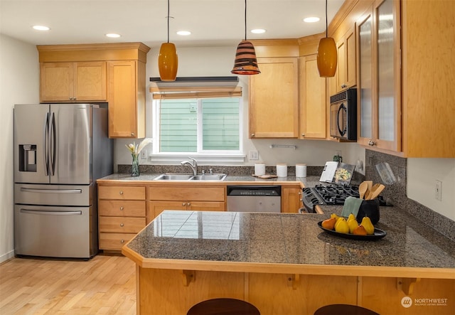 kitchen with sink, a breakfast bar area, hanging light fixtures, kitchen peninsula, and stainless steel appliances