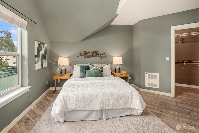 bedroom featuring lofted ceiling, wood-type flooring, a closet, and a walk in closet