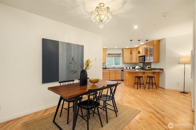 dining space with a notable chandelier, recessed lighting, light wood-style floors, and baseboards