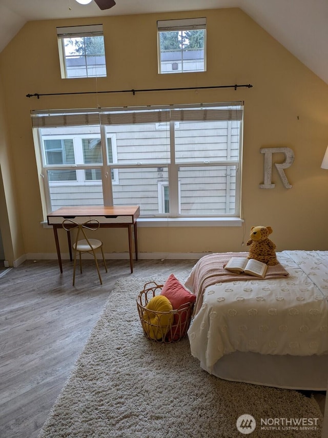 bedroom with baseboards, multiple windows, lofted ceiling, and wood finished floors