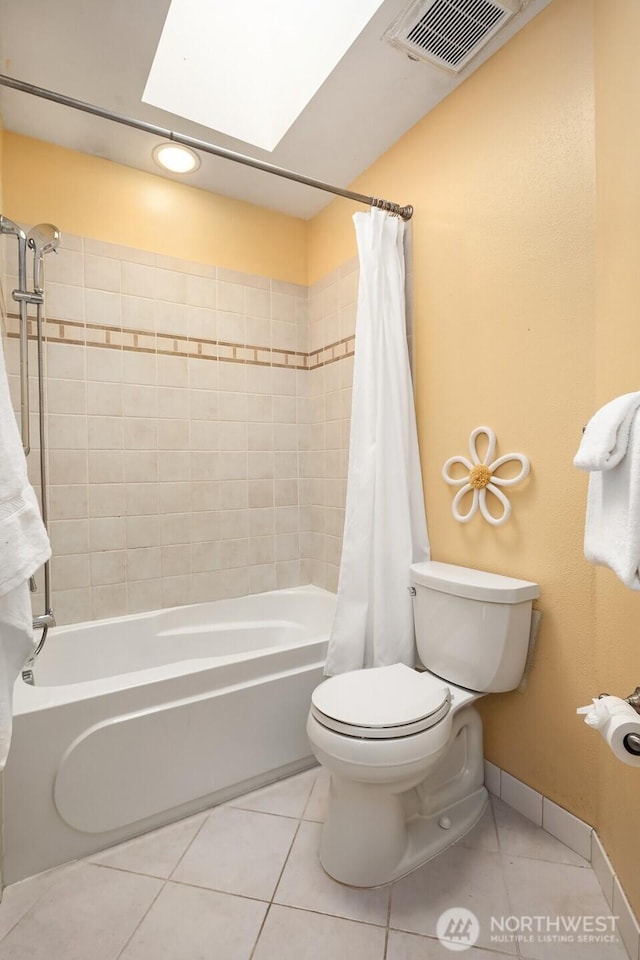 bathroom with a skylight, shower / bath combination with curtain, visible vents, toilet, and tile patterned floors