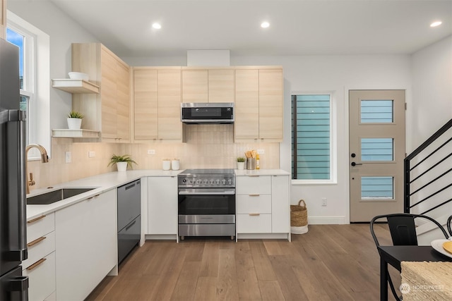 kitchen with sink, a wealth of natural light, stainless steel appliances, light hardwood / wood-style floors, and backsplash