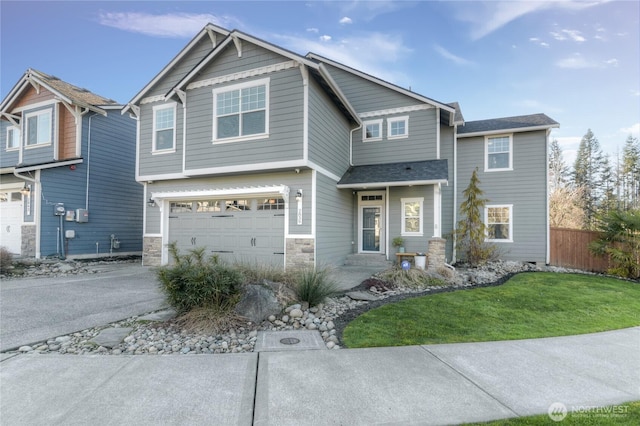 craftsman-style home featuring an attached garage, fence, a front yard, stone siding, and driveway