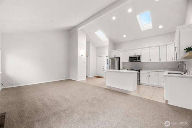 kitchen with appliances with stainless steel finishes, open floor plan, a kitchen island, and a sink