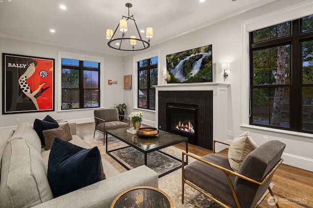 living area featuring a warm lit fireplace, light wood finished floors, baseboards, and crown molding