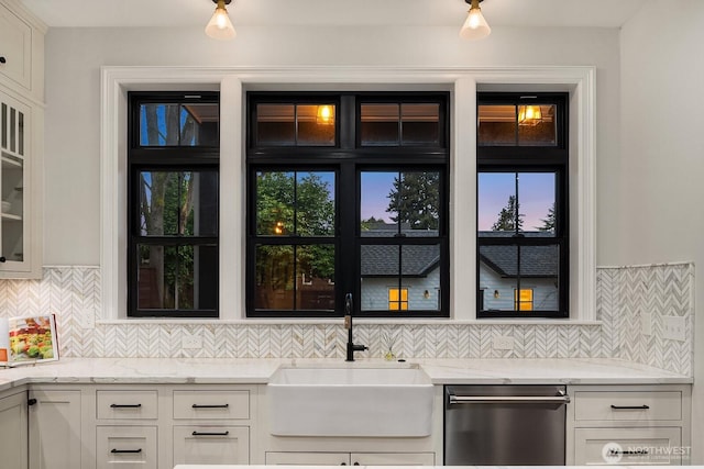 kitchen featuring light stone counters, a sink, white cabinets, decorative backsplash, and dishwasher