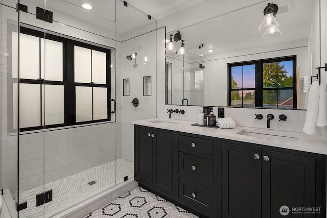 full bathroom with double vanity, a stall shower, and a sink