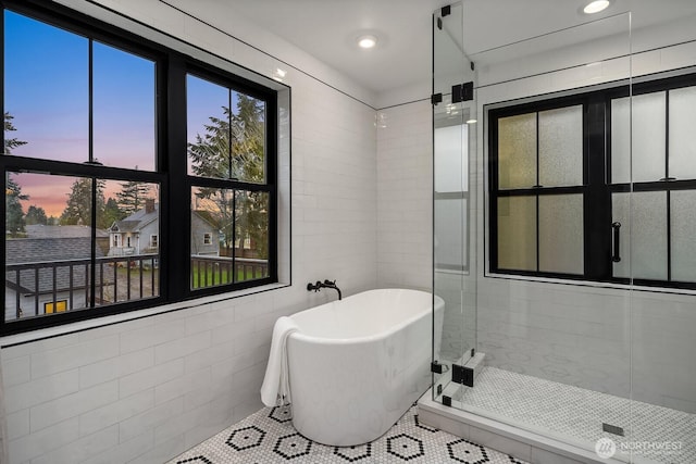 full bath featuring a freestanding tub, recessed lighting, tile walls, a shower stall, and tile patterned floors