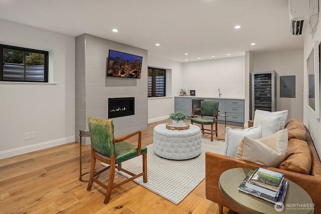 living area featuring light wood-type flooring, beverage cooler, a fireplace, and recessed lighting