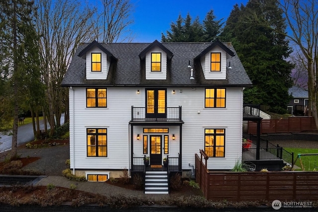 view of front of house featuring a balcony, a shingled roof, fence, and a porch